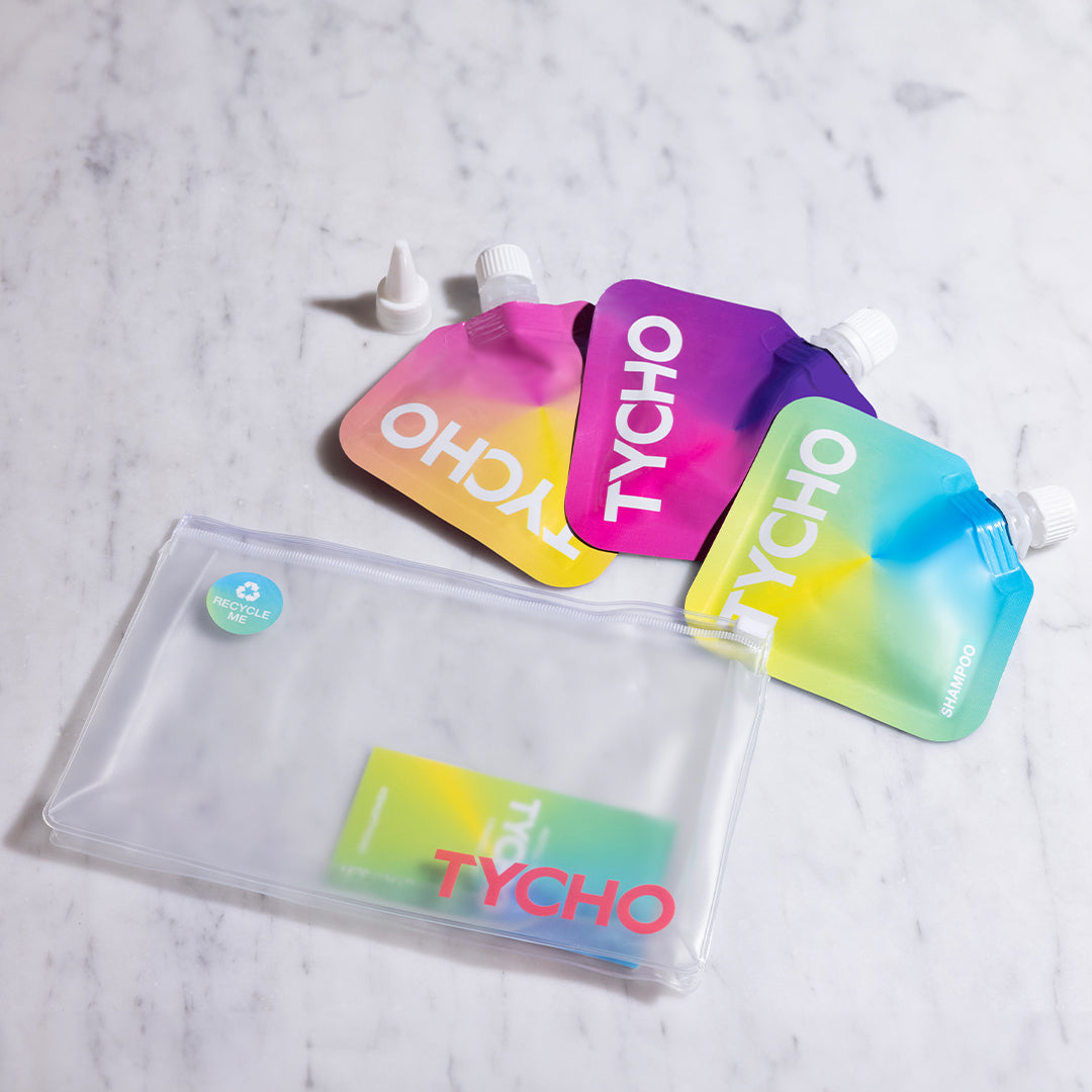 TYCHO's travel set pouches featuring sleek 30ml containers of shampoo, conditioner, and body wash, perfect for jet-setters looking for compact luxury