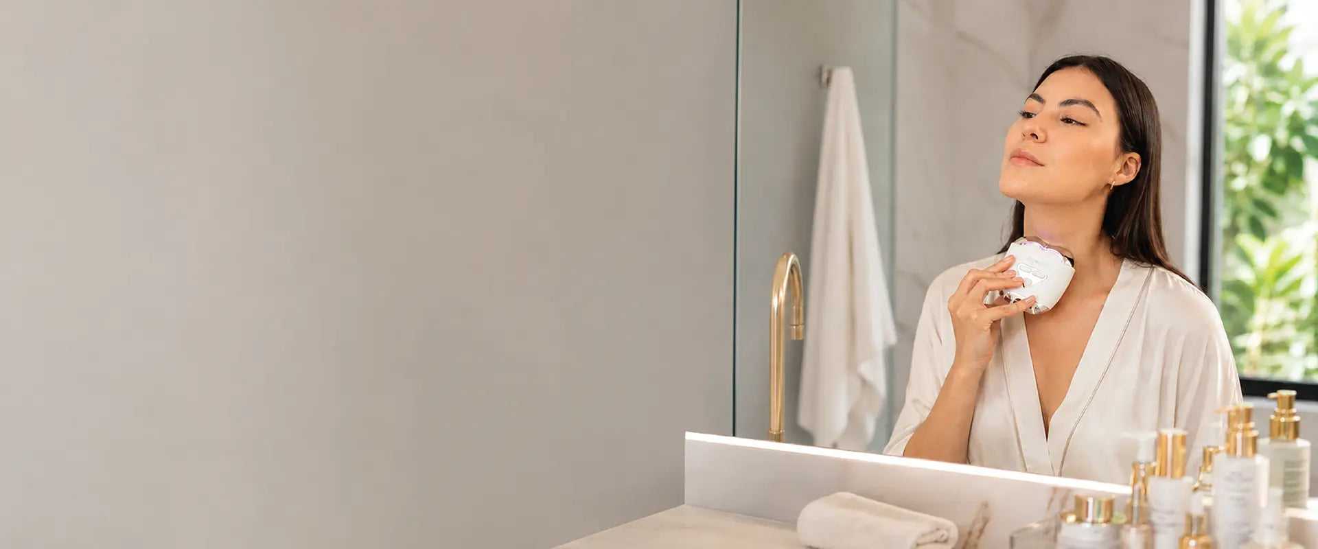 Woman using a RIKI facial device during a skincare routine at home